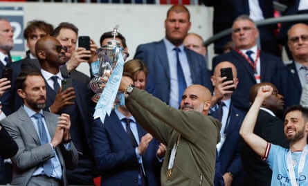 Pep Guardiola mengangkat Piala FA setelah kekalahan Manchester City dari Manchester United di final pada 3 Juni.