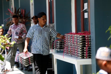 A man places bundles of meals in trays on a table