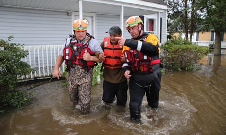 Lumberton North Carolina fire and rescue members help a resident walk through flooded waters in Lumberton, North Carolina on 17 September. 
