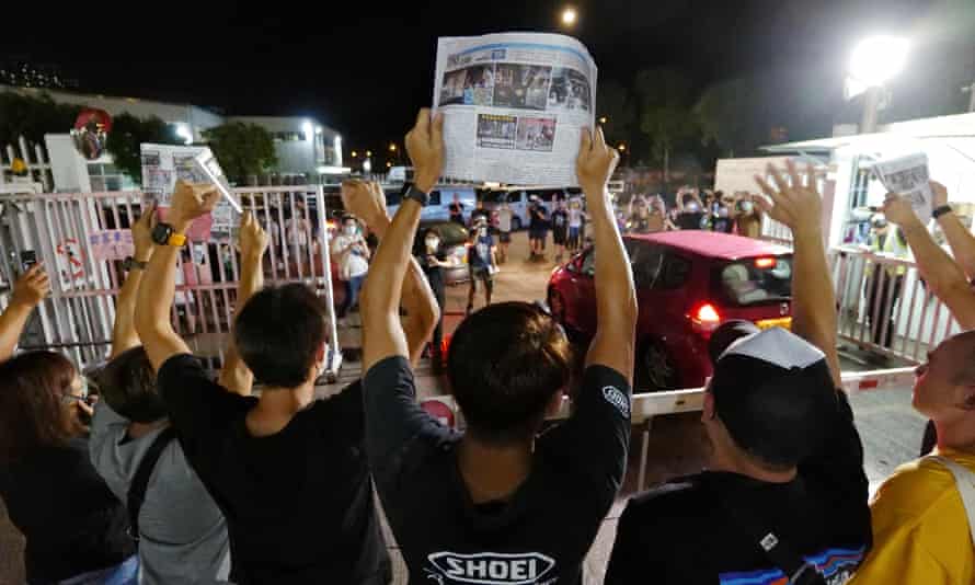 Apple Daily journalists hold freshly-printed copies of the newspaper’s last edition while acknowledging supporters gathered outside their office in Hong Kong as the tabloid is forced to close.