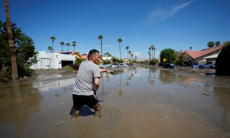 A man wades through a flooded suburban street.