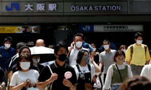 Pedestrians wearing protective face masks cross the road at Umeda district in Osaka, Japan.