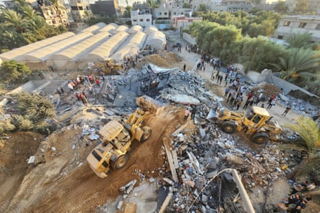 Palestinians stand by the rubble of a building destroyed in Israeli airstrikes in Deir el-Balah Gaza Strip.