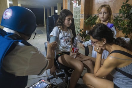 An Israeli paramedic checks the blood pressure of a young girl at residential building after it was hit by a rocket fired from Gaza Strip, in Ashkelon, southern Israel