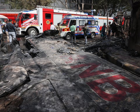 Wreckage of the Boeing 787 Dreamliner lies on the ground next to emergency vehicles and people