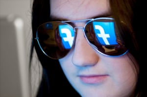 Someone wearing reflective sunglasses indoors with the facebook logo on their screen