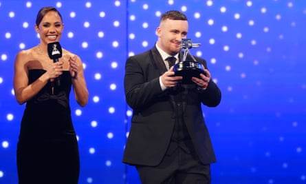 Luke Littler, alongside host Alex Scott, lifts the BBC Young Sports Personality of the Year award.