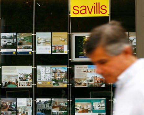 A pedestrian passes a branch of estate agent, Savills, in London in 2008.