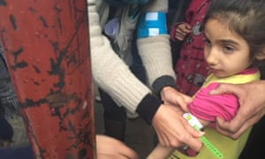 A Unicef employee measures the arm of a malnourished child in Madaya