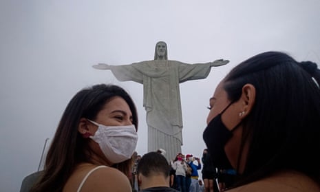 Tourists wearing face masks in front of the Christ the Redeemer statue in Rio