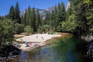 Visitors sunbathe at Merced River in Yosemite.