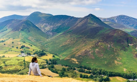 A hiker rests on Catbells in the Lake District looking over Newlands Valley.