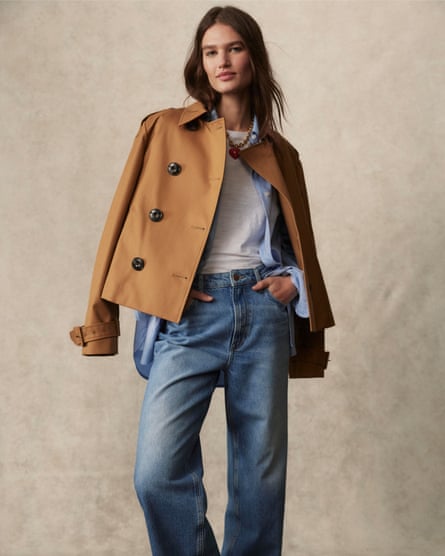 A model wearing a hazelnut cropped trench coat and blue denim jeans