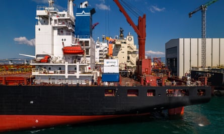 A crane pulls away above a white shipping container with the Seabound logo on it, which is on top of another container on the deck of a huge ship.