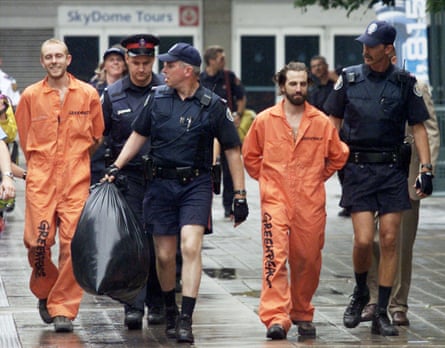 Guilbeault (kanan) dan sesama aktivis Greenpeace Chris Holden dikawal oleh polisi setelah mereka mendaki Menara CN di Toronto untuk memprotes kurangnya tindakan Kanada dan Amerika Serikat terhadap masalah lingkungan, 16 Juli 2001.