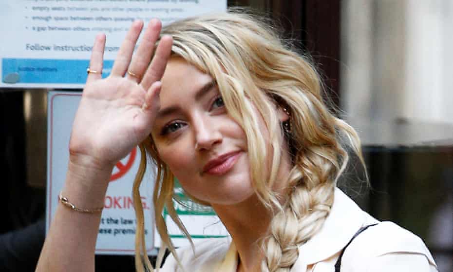 Amber Heard waves as she arrives at the high court in London