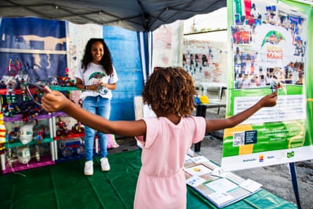 A young girl at an exhibition of homemade toys holds a length of string as a woman looks on