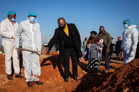 Mourners stand at the gravesite of a family member who died as a result of Covid-19 in Johannesburg, South Africa, on 24 July 2020.