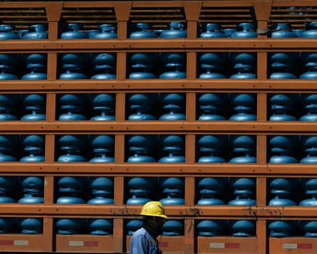 An oil refinery worker walks past a rack of gas cylinders