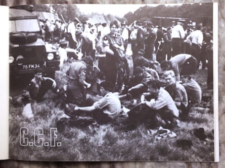 Foto bardh e zi e një grupi djemsh dhe mësuesish që qëndrojnë dhe ulen në një fushë të veshur me uniforma kadetësh.