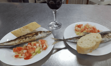 Seafood dishes and a glass of red wine on a serving counter at La Barraquilla, Almeria, Spain.