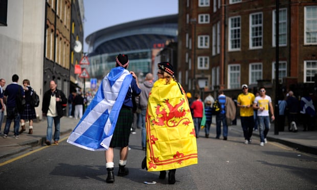 Two fans draped in Scotland fans approach a stadium