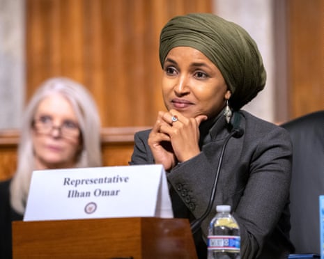 woman rests her chin on clasped hands during a congressional hearing