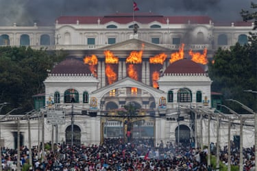 Flames arise from a governement building surrounded by protesters