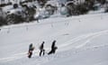 Snowboarders walk up hill
