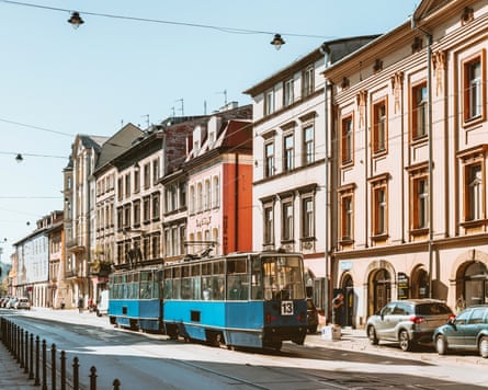 An old-style blue tram passes the facades of coloured three-storey buildings
