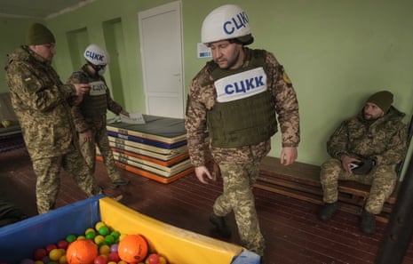 Members of the Joint Centre for Control and Coordination on ceasefire of the demarcation line survey a gym damaged by shelling near a school in Vrubivka.