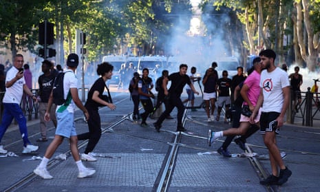 Protesters disperse amid smoke from tear gas canisters.