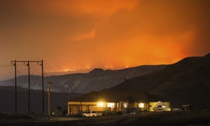 A wildfire burns on a mountain in the distance east of Cache Creek