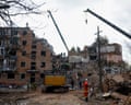Rescue workers and cranes search a collapsed Pryluky apartment building for survivors beneath debris