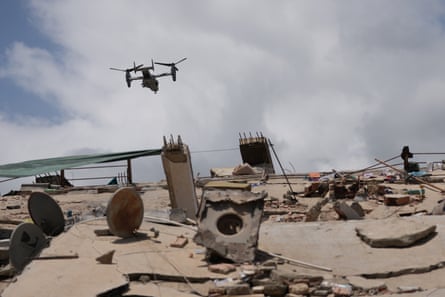 A drone flying above piles of concrete and other debris.