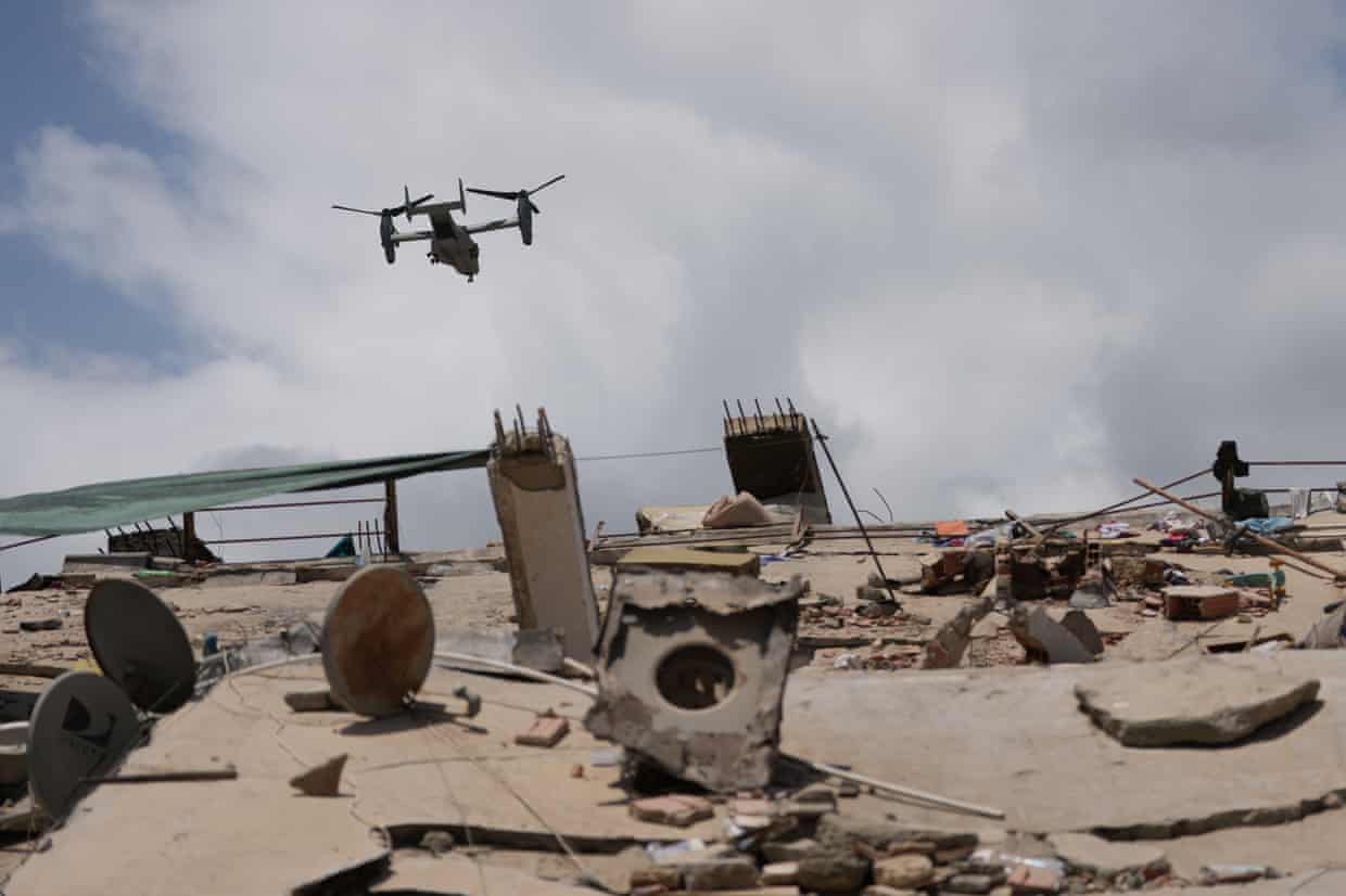 A drone flying above piles of concrete and other debris.