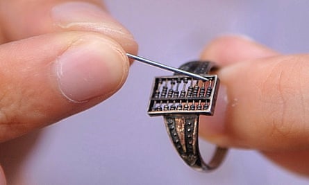 A person uses a pin to move the beads of a silver ring abacus of 1.2 centimeter long and 0.7 centimeter wide, dating back to Chinese Qing Dynasty