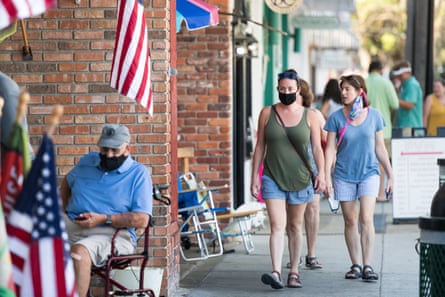 People walk down the sidewalk in St Simons Island, Georgia, on 17 July. Brian Kemp made an order earlier in the week that forbade municipal officials from setting mandatory face-covering policies.