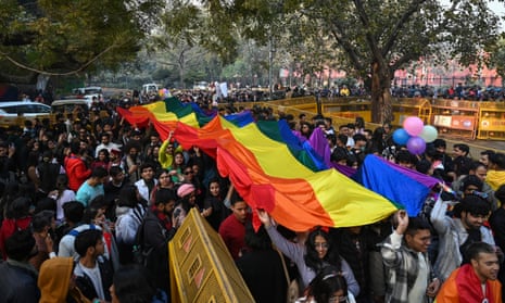 Members of the LGBTQ community and their supporters carry a rainbow flag as they march in January 2023