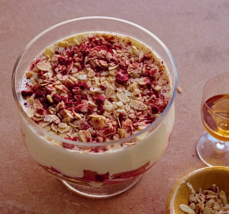A glass bowl filled with trifle, with other dishes and glasses on the table