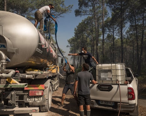 Volunteers fill a water tank from a truck as nearby firefighters work to extinguish flames in a forest in Claouey, near Lège-Cap-Ferret, France.