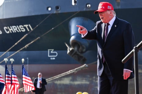 a man in a suit points while standing near an oil tanker