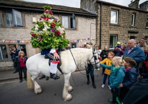 Ceremonial king, Jon Haddock, wears a large flower-covered framework while leading a procession on horseback during the Castleton Garland
