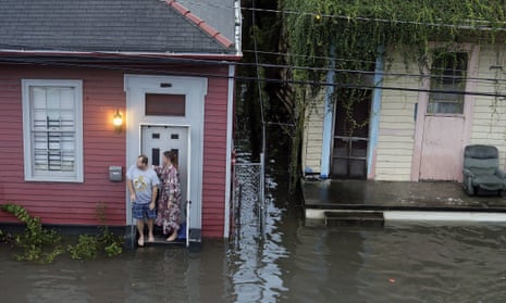 People stand outside their home in floodwaters in New Orleans on 5 August.