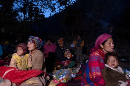 Women hug small children on a hillside at night