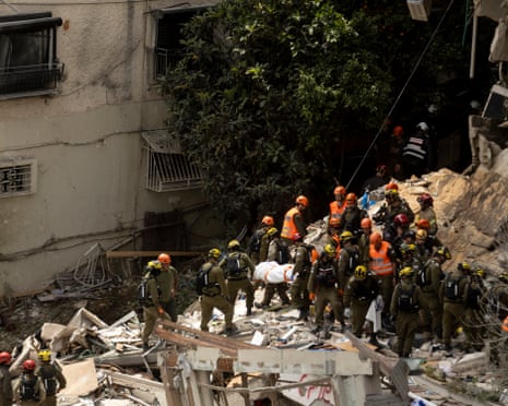 Ισραηλινοί ανταποκριτές έκτακτης ανάγκης μεταφέρουν ένα νεκρό μετά την ανάκτηση από ένα κτίριο κατοικιών μετά από προφανή επίθεση ιρανικού βαλλιστικού πυραύλου στη Χάιφα.