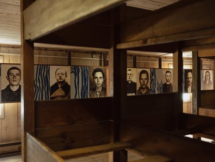 Photographs of prisoners on wooden walls, with  wooden bunkbeds in the foreground
