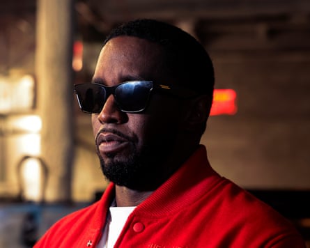Sean Combs usando óculos de sol escuros e uma jaqueta vermelha sobre uma camiseta branca