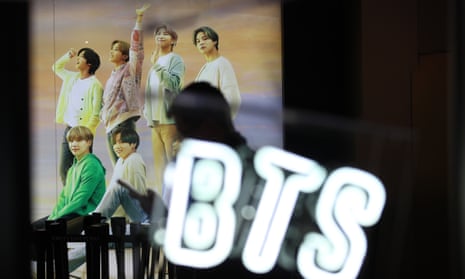 A woman walks past a photo of K-pop boy band BTS at an apartment store in Seoul