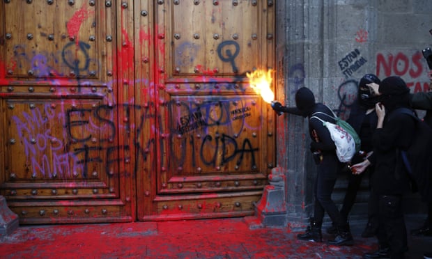 A masked female protester sprays fire at the entrance to the national palace in Mexico City on 14 February.